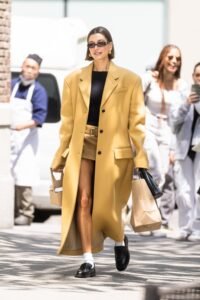 The supermodel and founder of Rhode, Hailey Bieber, has won over the globe with her flawless street fashion looks. Hailey Bieber has established herself as a fashion star with her distinctive style elements, like Jennifer Fisher gold hoops, stylish sunglasses, and a propensity for adopting the most recent trends. Her collaboration with stylist Dani Michelle, who has assisted her in creating an impressive wardrobe, may be credited for an important part of her success in the fashion world.While Hailey effortlessly rocks her street style, she also knows how to make a statement on the red carpet. Working closely with stylist Karla Welch, whose longtime client happens to be her husband, Justin Bieber, Hailey consistently dazzles in coordinated ensembles. Whether it's for a romantic date night or a high-profile event, Hailey and Justin always manage to turn heads. Their 2019 wedding in South Carolina was a testament to their fashion-forward sensibilities, with Justin donning a sleek Celine tuxedo and Hailey stunning in an intricate Off-White wedding dress designed by the late Virgil Abloh. The dress featured a veil embroidered with Abloh's signature quotation marks and a heartfelt message: "Till death do us part."

Hailey Bieber is working in the fashion business in addition to her projects as a member of Victoria's Secret's VS Collective. She enthusiastically represents Tiffany & Co. as an ambassador and models intimate apparel for the venerable brand. In particular, Hailey like slip dresses and micro minidresses, frequently choosing styles from the well-known fashion label Saint Laurent. She also has a keen eye for accessories and regularly uses items from the brand to complete her outfits.

Also Read: Julia Fox Advocates for Safe Sex in Fashion with Latest Condom-Inspired Outfit

Hailey Bieber wore a camel-colored outfit with striking black embellishments for her most recent visit to New York City. She showed off her sense of style by wearing a low-rise, micro miniskirt from Prada with a belted light-brown Khaite coat.

The fashion industry continues to be influenced and inspired by Hailey Bieber's style choices. She radiates grace and elegance with effortlessness, whether she's walking down the street or gracing the red carpet. Hailey has established herself as a real fashion mogul because of her intuitive sense of style and collaborations with brilliant stylists, leaving admirers eagerly anticipating her next stylish outfits.
